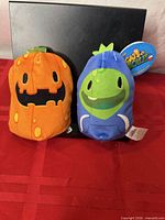 Front view of both plush toys upright on red cloth