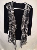 Front view of black and white geometric open-front cardigan on hanger