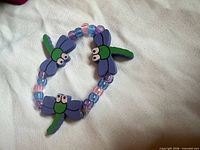 Bracelet laid flat showing four wood dragonfly charms and multicolour beads