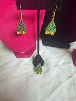 Front view of two Christmas tree earrings on stand with matching brooch below