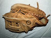 Palm side of tan leather glove with baseball seated in pocket, showing printed text and lacing