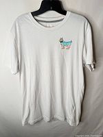 Front view of white T-shirt showing small crowned goat chest graphic