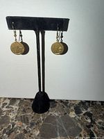 full view of both gold-tone coin earrings on stand
