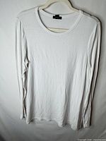 Front view of white long-sleeve top on hanger