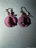 Front view of both earrings showing pink discs, bead stack, and copper hooks