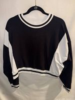 Front view of black and white cropped sweatshirt on hanger