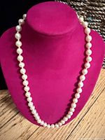 Full view of faux pearl necklace on display bust