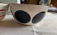 Side view of white stoneware bowl showing large black polka dot pattern