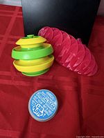 Close view of Lab Putty tin, green/yellow spinner, pink spiral toy