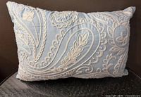 Front of pillow showing light blue fabric and ivory paisley embroidery