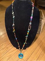 Front view of full beaded necklace on display bust highlighting pendant and bead variety