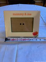 Front view of Mommy & Me picture frame with tape measure showing 3 x 5 in opening