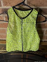 Front view of neon green sequin vest on hanger