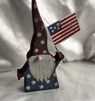 Front view of painted wooden gnome holding American flag