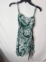 Front view of green and white tropical leaf print SHEIN sundress hanging on hanger