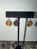 Front view of earrings on stand showing amber crystal drops
