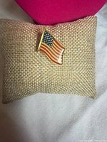 Front view of enamel American flag lapel pin on display cushion