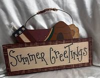 Front of painted wooden wall sign showing text, decorative watermelon accent and wire hanger