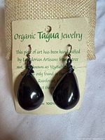 Front view of pair of tagua teardrop earrings on backing card