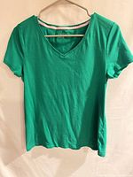 Front view of green V-neck short-sleeve top on hanger