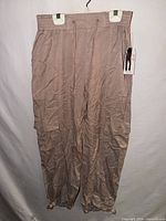 Front view of mauve Tencel jogger pants showing waistband, pockets, cuffs and attached retail tag