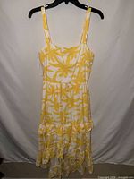 Full front view of the yellow and white palm print maxi dress on hanger