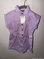 Front view of lavender Vince Camuto infant romper with tags attached