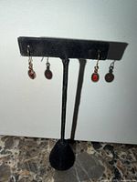 Full view of pair of earrings on stand