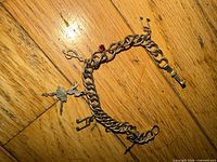 Overall view of two-tone charm bracelet showing chain, ballerina charm, keys, red rhinestone accent and clasp