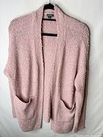 Front view of pink chenille open-front cardigan with pockets on hanger
