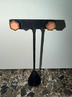 Pair of wooden and peach enamel hexagon stud earrings on display stand