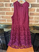 Front view of burgundy lace dress on hanger