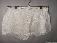 Front view of white lace shorts on hanger