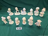Group shot of all 12 Precious Moments figurines on green backdrop