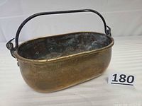 Full view of oval brass pot with iron bail handle