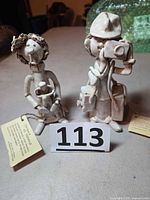 Both Dino Bencini figurines side by side with lot number and tags visible