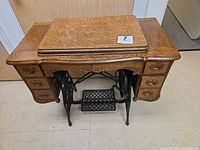 Closed oak cabinet showing refinished surface and treadle base
