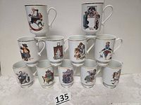 Front view of all eleven mugs showing different Norman Rockwell scenes