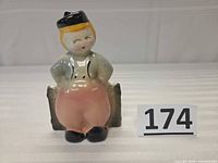 Front view of ceramic Dutch boy planter next to lot number