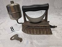 Full view of sad iron with attached fuel tank and wrench