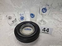 Group shot of all items: tire ashtray plus four promotional glasses