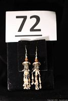 Full view of both sterling silver bead dangle earrings hanging on display