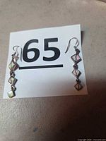 Front view of both earrings next to size marker