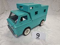Front-side view showing overall truck, wheels, camper top, numbering card 9