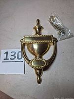 Front view of polished brass door knocker with hardware bag