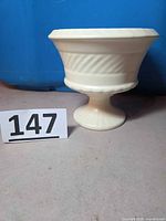 Front view of Haeger off-white footed vase planter