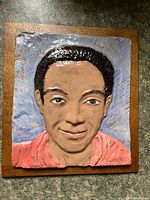 Front view of ceramic relief portrait on wood backing