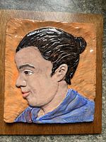 Front view of ceramic relief portrait on wood backing