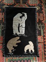Front of black wool wall hanging showing applique polar bears and Inuit hunter with blanket stitch border