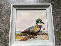 Front view showing framed relief carving with painted landscape